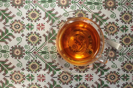 glass cup with tea on a beautiful tablecloth top view
