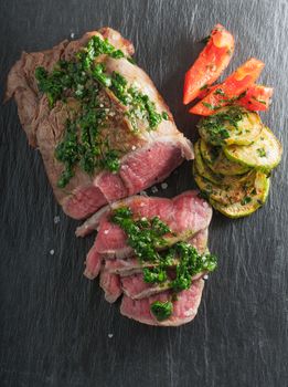 Roast Beef dinner with roasted zucchini, pepper and salsa verde on a stone plate