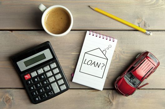 Notepad with loan question inside a sketch of a house with a miniature car and calculator 