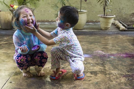 Two Indian kids with their face smeared with colors celebrate Holi, the festival of colors.