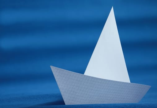 origami white paper yacht on blue sea 