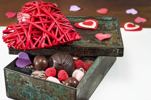 Sweets and decorative hearts for Valentine's day, in an old iron box. Selective focus, close-up.