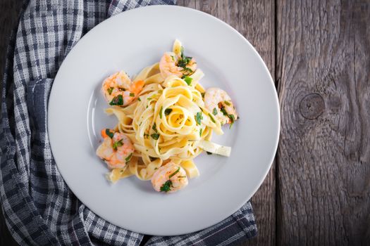 Tagliatelle with shrimps served on a wooden surface