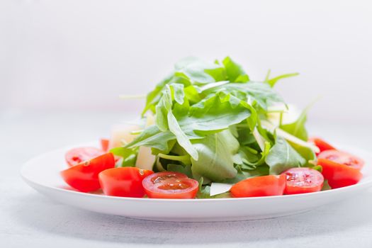 Salad with arugula, tomatoes on a white background