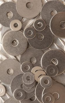 Background abstract pattern and texture of numerous overlapping stainless steel washers in an overhead full frame view