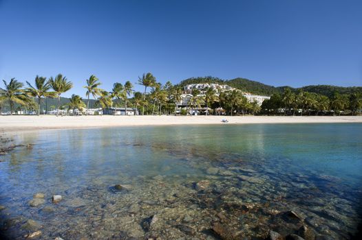 View of beautiful Airlie Beach, Queensland, Australia with its white sands fringed by tropical palms on a sunny summer day in a travel concept