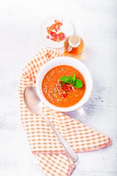 Bowl of fresh tomato soup gazpacho on a white surface