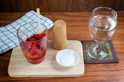 fresh split strawberries mixed with sugar and salt in glass cup.  Fruit snack thai food.