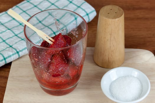 fresh split strawberries mixed with sugar and salt in glass cup.  Fruit snack thai food.