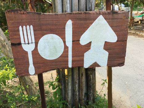 Blank wooden rustic style sign of white plate, folk and knife. wood signboard from cafe restaurant.