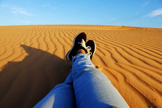 Summertime background with woman foot on sand hill, people relax on orange sandy under blue sky at Mui Ne, Phan Thiet, Vietnam, summer is coming and a trip to adventure make awesome life 