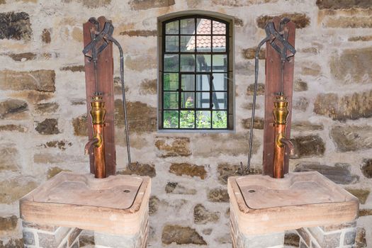 Two antique copper hand pumps in an old building.