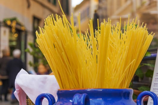 Bundle of uncooked dried Italian spaghetti in a jar in the ancient streets of Rome