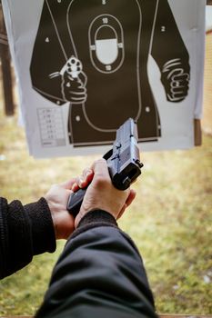 Close-up of a man hands holding and loading gun magazine in the pistol at the shooting range.