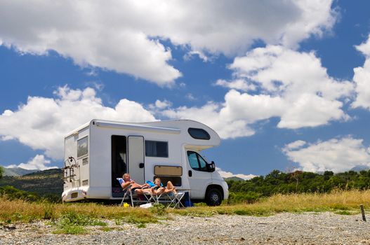 couple is sunbathing in front of a motor home