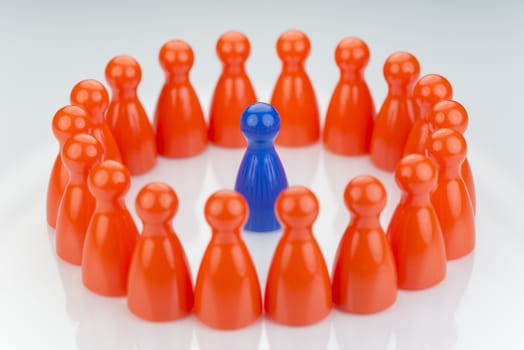 Conceptual orange game pawns and a blue play pawn as abstract display of inequality in color and number of
