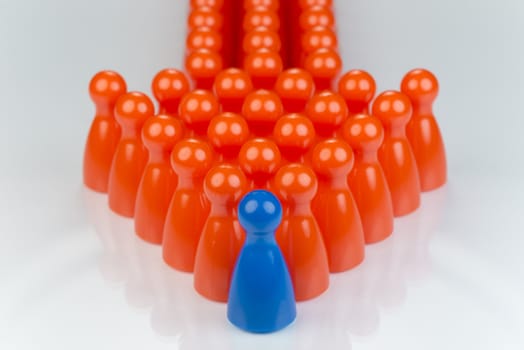 Conceptual orange game pawns and a blue play pawn as abstract display of inequality in color and number of
