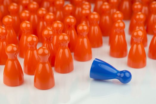 Conceptual orange game pawns and a blue play pawn as abstract display of inequality in color and number of
