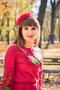 portrait of a beautiful, girl with long straight hair in a red short dress in the park in autumn