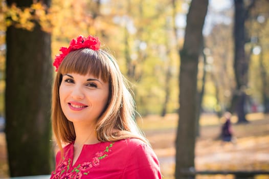 portrait of a beautiful, girl with long straight hair in a red short dress in the park in autumn