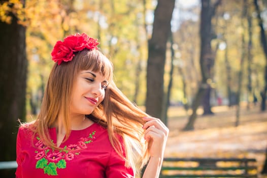 portrait of a beautiful, girl with long straight hair in a red short dress in the park in autumn