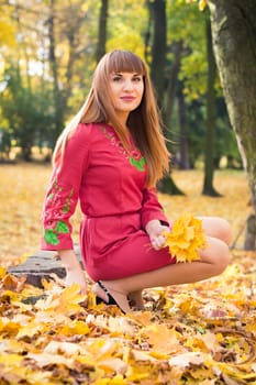 portrait of a beautiful, girl with long straight hair in a red short dress in the park in autumn