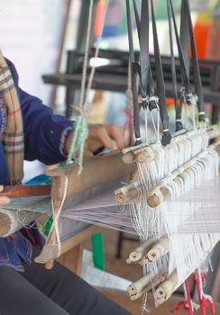 Close up of  woman weaving white pattern on loom in Chiang Mai Thailand