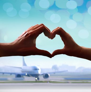 Silhouette of hands in form of heart when sweethearts have touched at airport