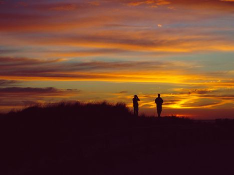 Silhouette of two people looking the sunset beach.