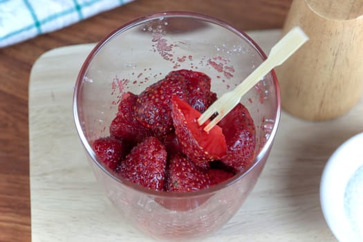 fresh split strawberries mixed with sugar and salt in glass cup.  Fruit snack thai food.