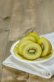 golden kiwi fruit and sliced on dish over wooden background