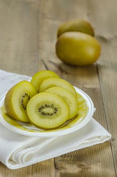 golden kiwi fruit and sliced on dish over wooden background