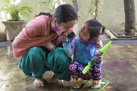 Mother and daughter with their face smeared with color celebrate Holi, the festival of colors in India.