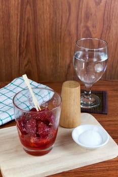 fresh split strawberries mixed with sugar and salt in glass cup.  Fruit snack thai food.