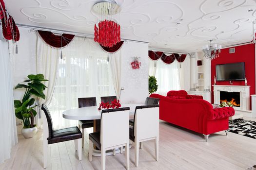 Classical living room interior in white and red colors with dinner table and fireplace