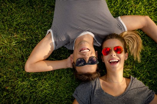 Portrait of a young beautiful couple lying on the grass