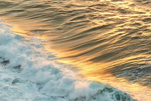 Golden reflections of the sun on a wave at sunset