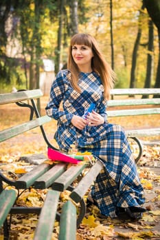 beautiful, dreamy girl with long straight hair in a blue long dress in the park in autumn