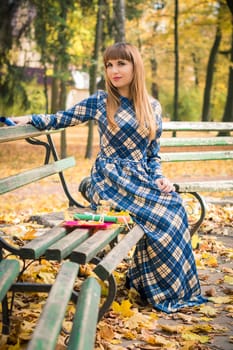 beautiful, dreamy girl with long straight hair in a blue long dress in the park in autumn