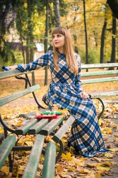 beautiful, dreamy girl with long straight hair in a blue long dress in the park in autumn