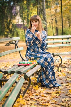 beautiful, dreamy girl with long straight hair in a blue long dress in the park in autumn