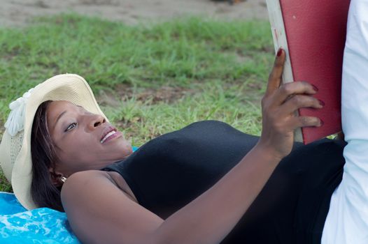 This young woman lying in the shade of a tree is reading quietly.