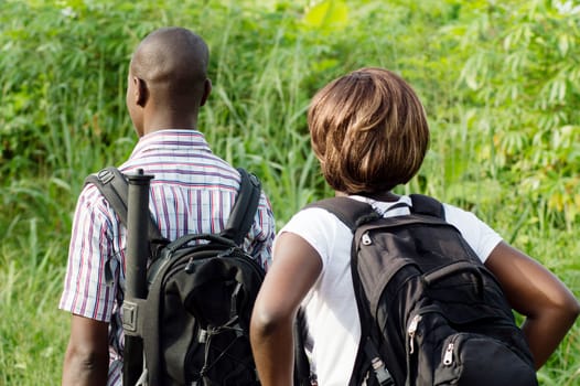 a couple of young hand  ride in the bush with bags back.