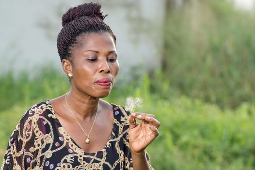 This young woman blowing the flower she hold in her hand.