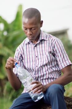 This young  man open the bottle of water to drink.