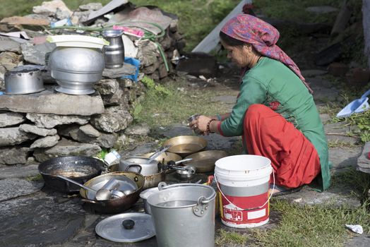A woman cleaning utensils outdoor in Shimla, Himachal Pradesh, India.