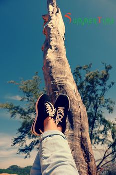 Girl travel alone and enjoy summertime by raise legs up to sky, people relax under tree to happy summer holiday