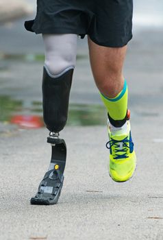 Man running with prosthetic leg on the street.