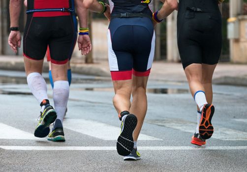 Group of marathon runners on the street. Back view.