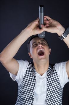 Young black-haired man dressed in black and white performs singing to microphone